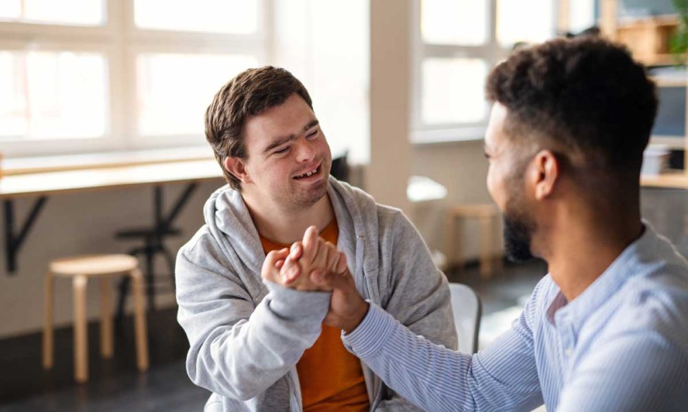 support worker shakes hands with man with disability